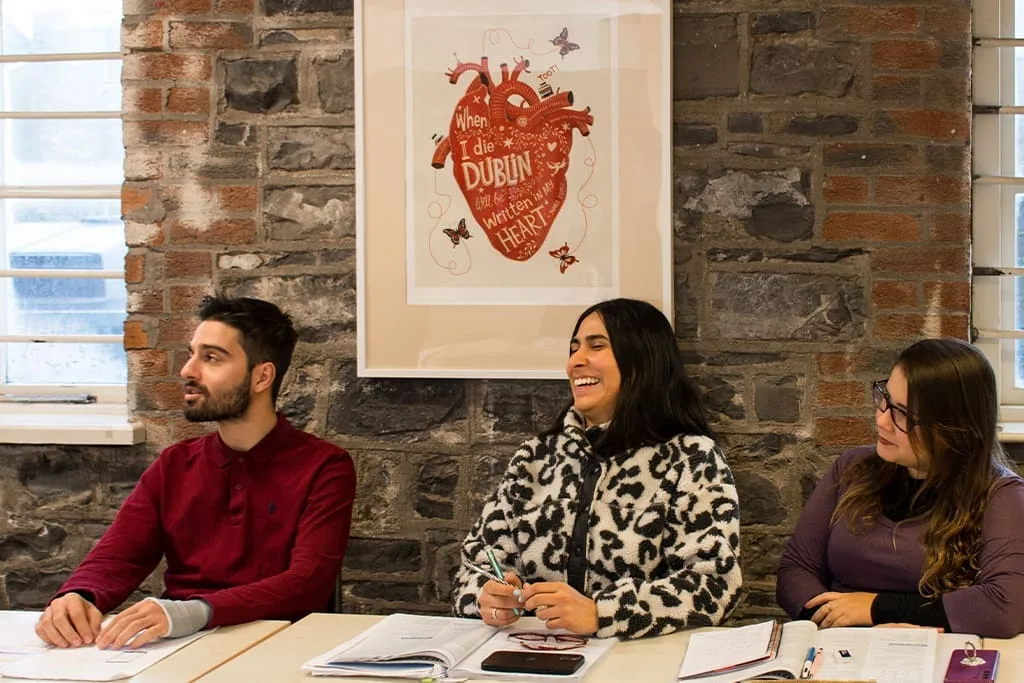 Students participating in an English class at ISI Dublin, sitting in a classroom with exposed stone walls