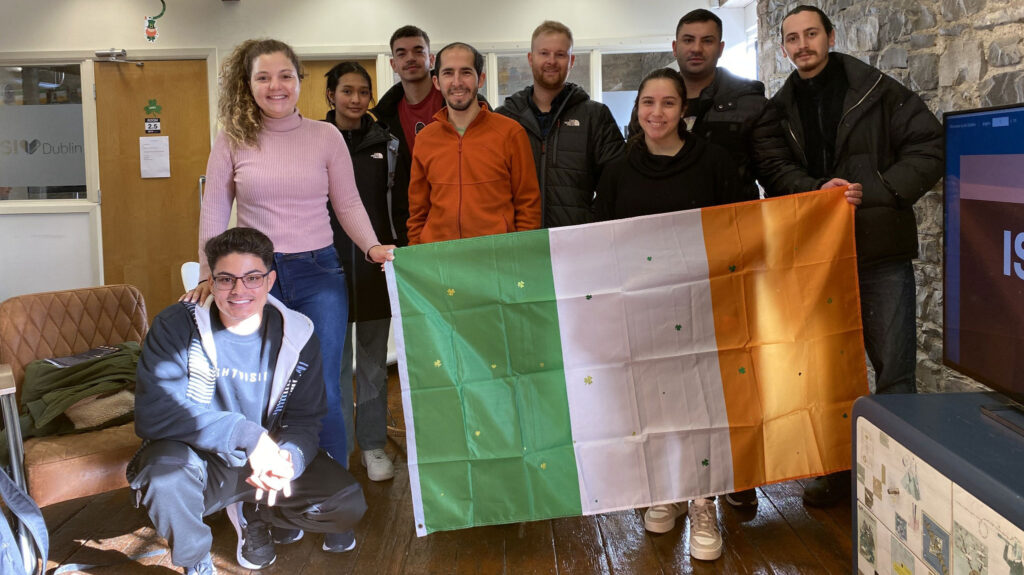 Internationale Studierende, die im Innenbereich zusammen mit einer irischen Flagge posieren, bei ISI Dublin